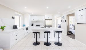 a kitchen with white cabinets and black stools