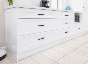 a white kitchen counter with drawers and a microwave