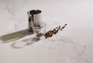a glass cup and a glass with coffee beans on a marble surface