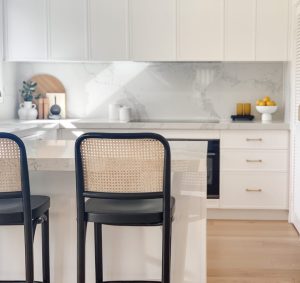 a kitchen with white cabinets and chairs
