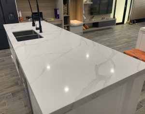 a white counter top with a sink and a black faucet