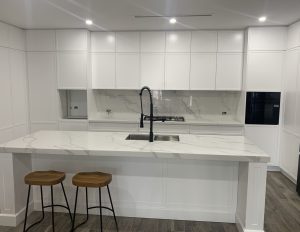 a white kitchen with a sink and stools