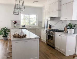 a kitchen with white cabinets and marble counter tops