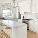 a kitchen with white cabinets and marble countertops