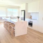 a kitchen with a white island and stools