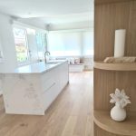 a white kitchen with a white counter and a white vase