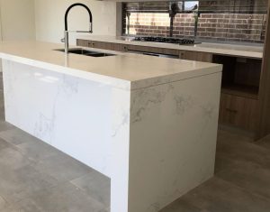 a white kitchen island with a black faucet