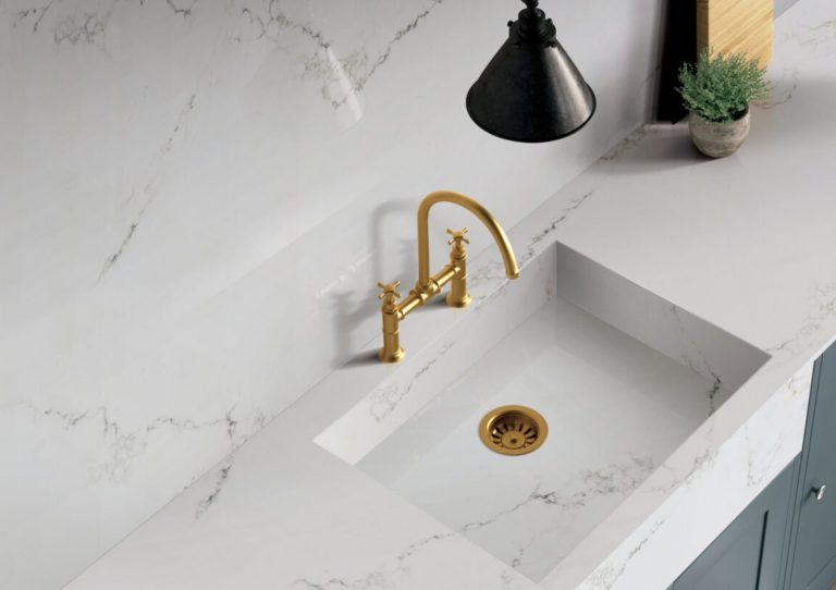a sink with a gold faucet and a black lamp