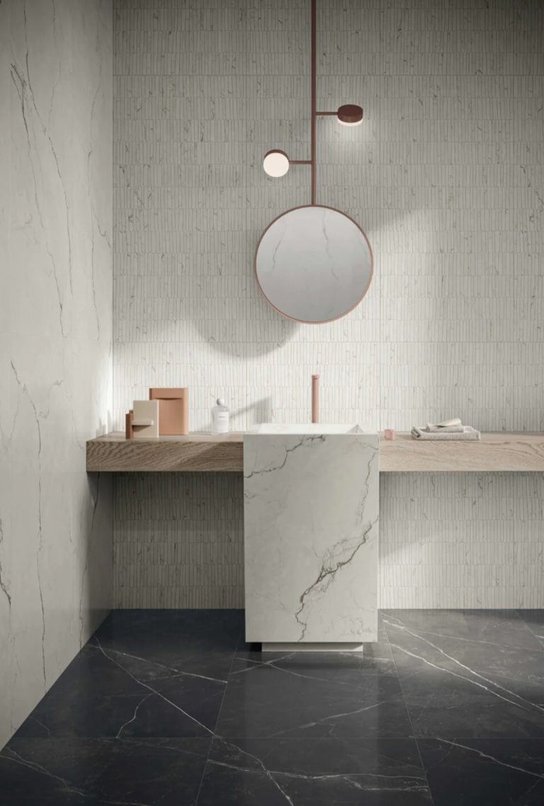 a bathroom with marble counter top sink and round mirror