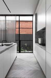 a kitchen with white cabinets and marble counter tops