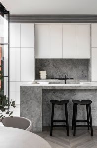 a kitchen with white cabinets and black stools