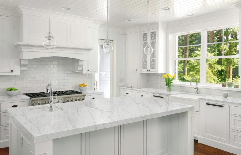 a kitchen with white cabinets and marble counter tops